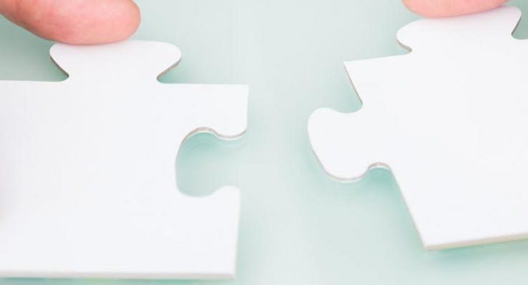 Hands holding two white puzzle pieces