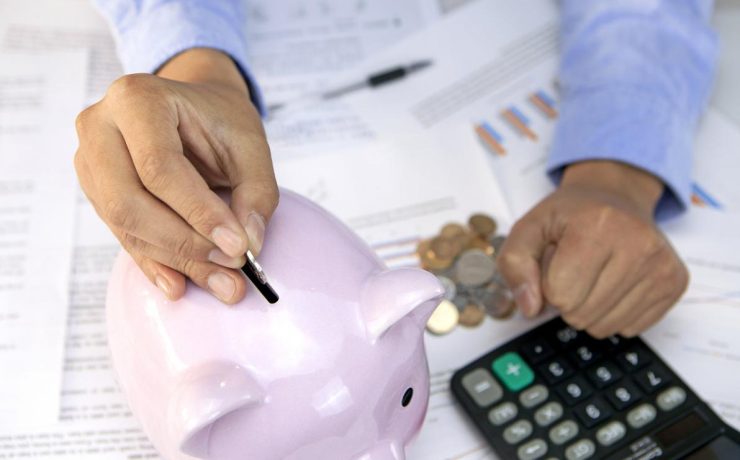 Person putting coins into a piggy bank