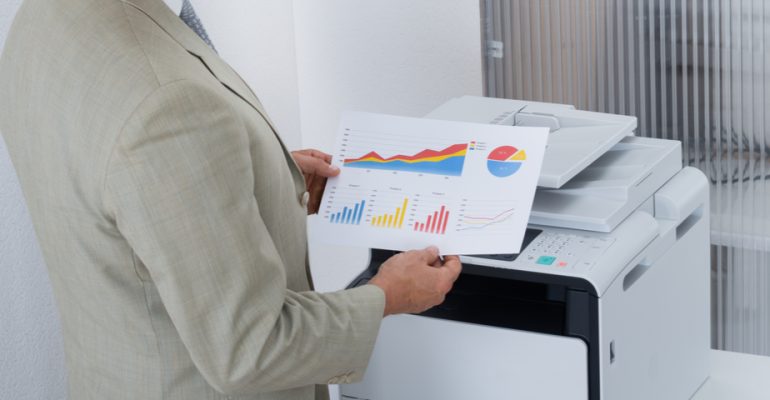 holding papers in front of printer