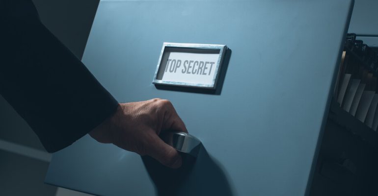 Man pulling out drawer on filing cabinet that says top secret