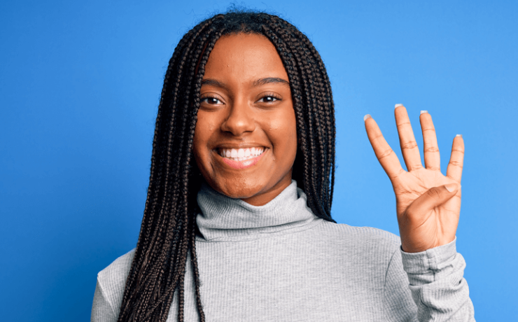 Woman holding up four fingers smiling on a blue background