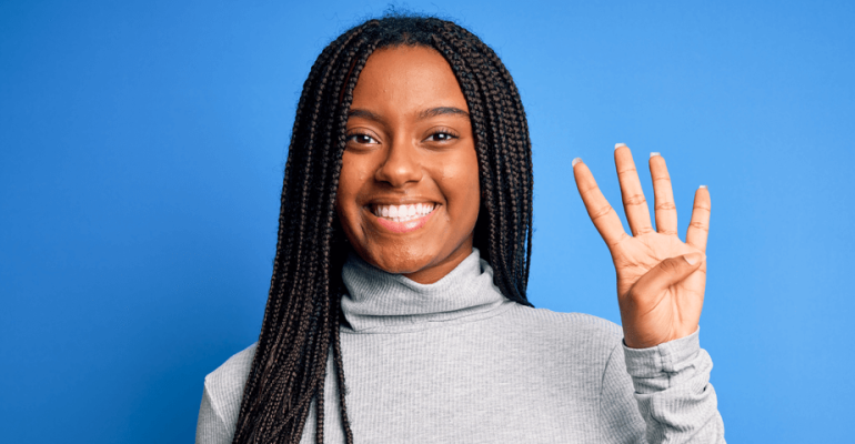 Woman holding up four fingers smiling on a blue background