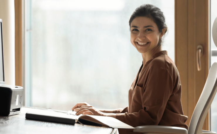 Young woman smiling, sitting on chair at office desk