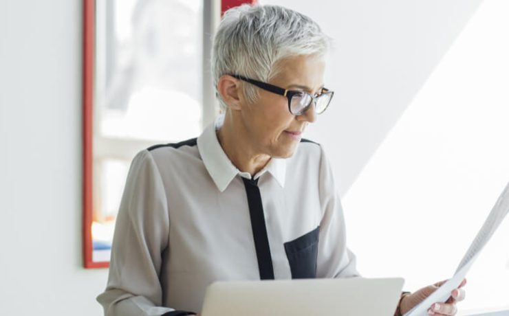 Female looking at paper while working on laptop