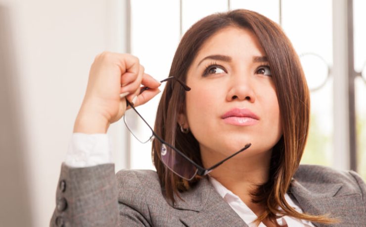 Business woman thinking while holding glasses up to face