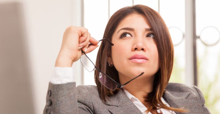 Business woman thinking while holding glasses up to face