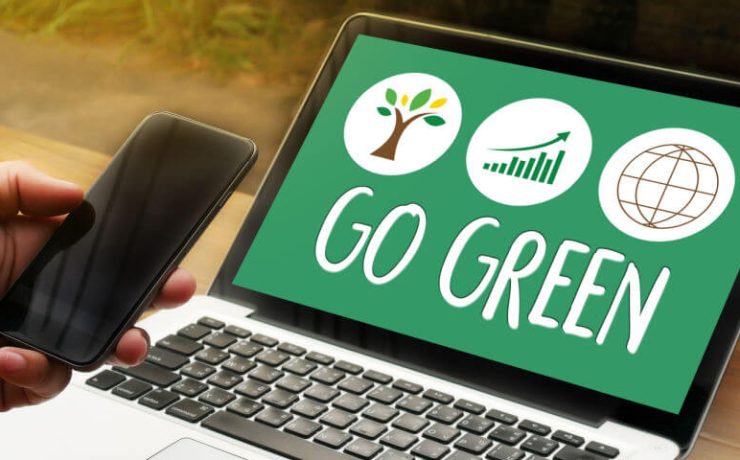 Open laptop with the words Go Green on the screen and a person's hand holding a smart phone
