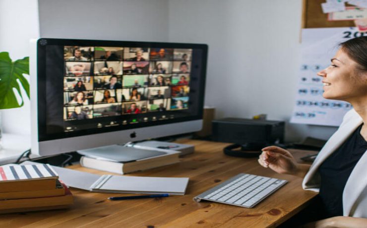 Woman at desk smiling having a video conference call with many people