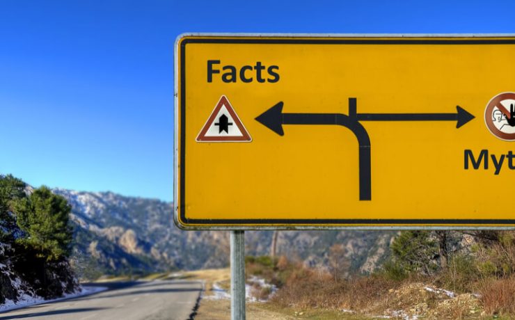 Yellow road sign on highway pointing the way to Facts and Myths