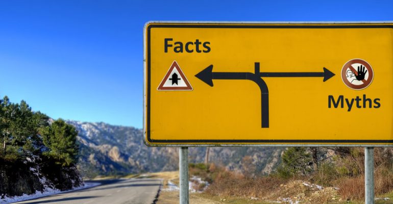 Yellow road sign on highway pointing the way to Facts and Myths