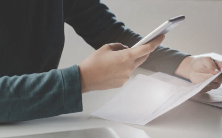 Person holding smart phone and looking at a document
