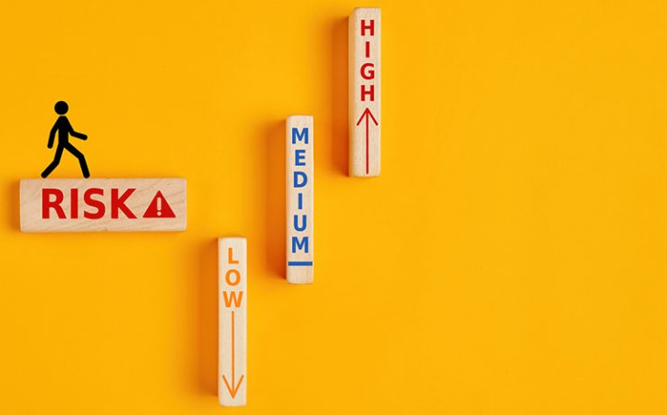 Silhouette of a person walking on a wooden block that says risk