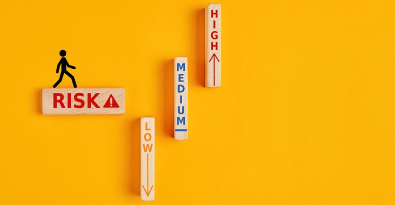 Silhouette of a person walking on a wooden block that says risk