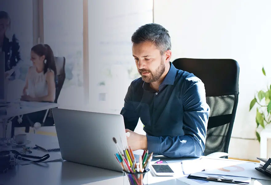 Close up of man in office at his desk working on a laptop