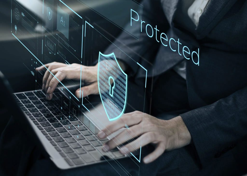 Close up of man's hands typing on a laptop keyboard with a lock-shield icon and the word protected as an overlay