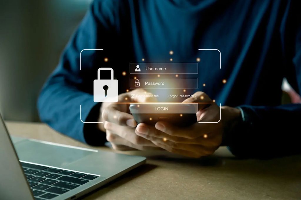 Man typing on smart phone there is a laptop in front of him and an overlay of a login screen with a lock icon