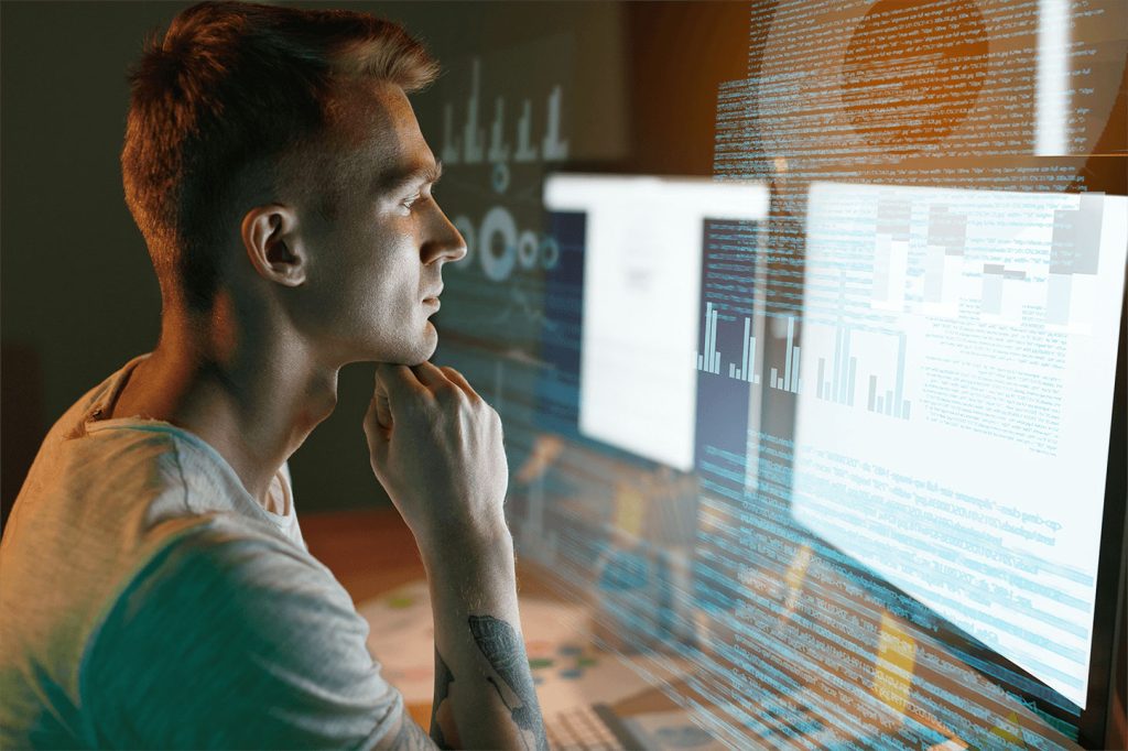 Man reviewing code on several different computer monitors