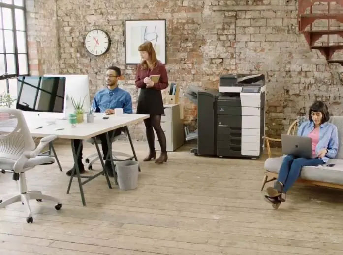 Three people in a modern office with exposed brick walls