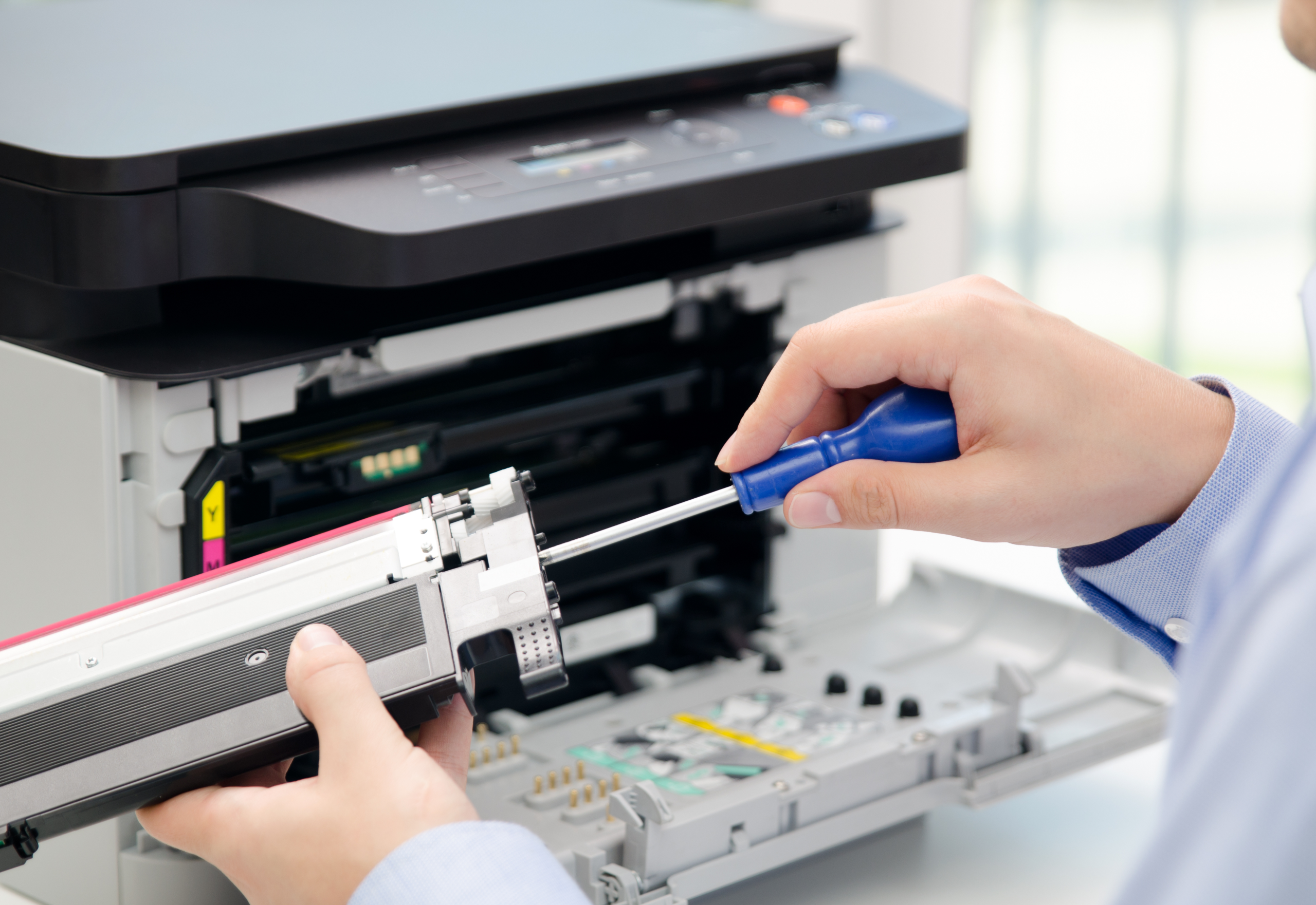 Printer with front opened so that a man can work on a part which is in his hand.