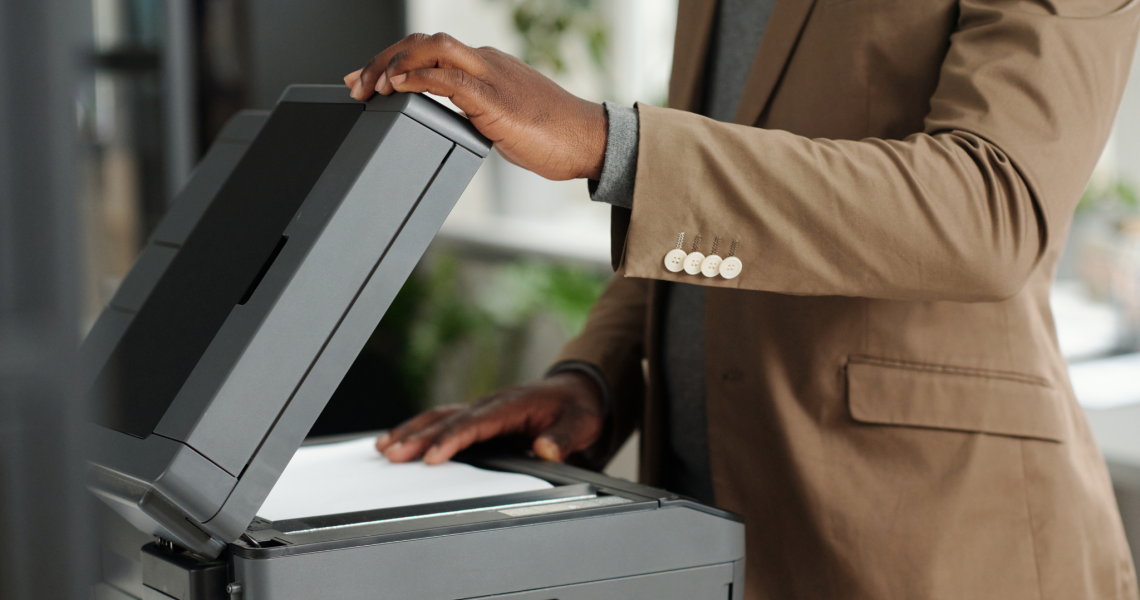 Office employee reviewing documents on a copier, showing signs of when to replace an office copier