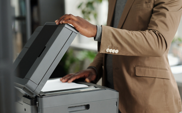 Office employee reviewing documents on a copier, showing signs of when to replace an office copier