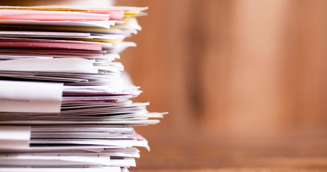 Many stacked documents on a table.