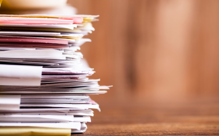 Many stacked documents on a table.
