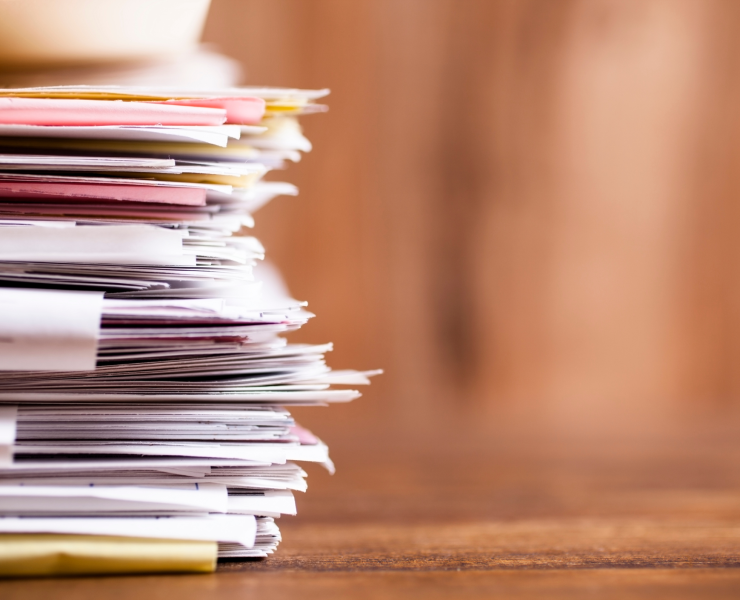 Many stacked documents on a table.