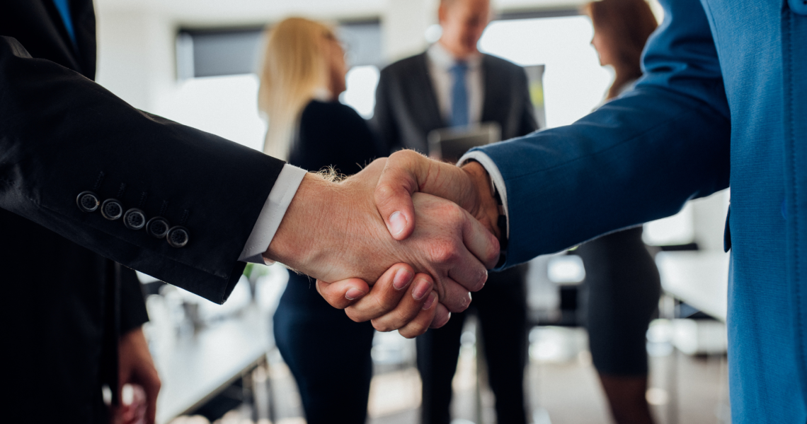 Two business professionals shaking hands in an office, representing a partnership with one provider for IT and print services